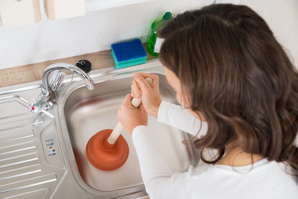 Woman unclogging the kitchen sink