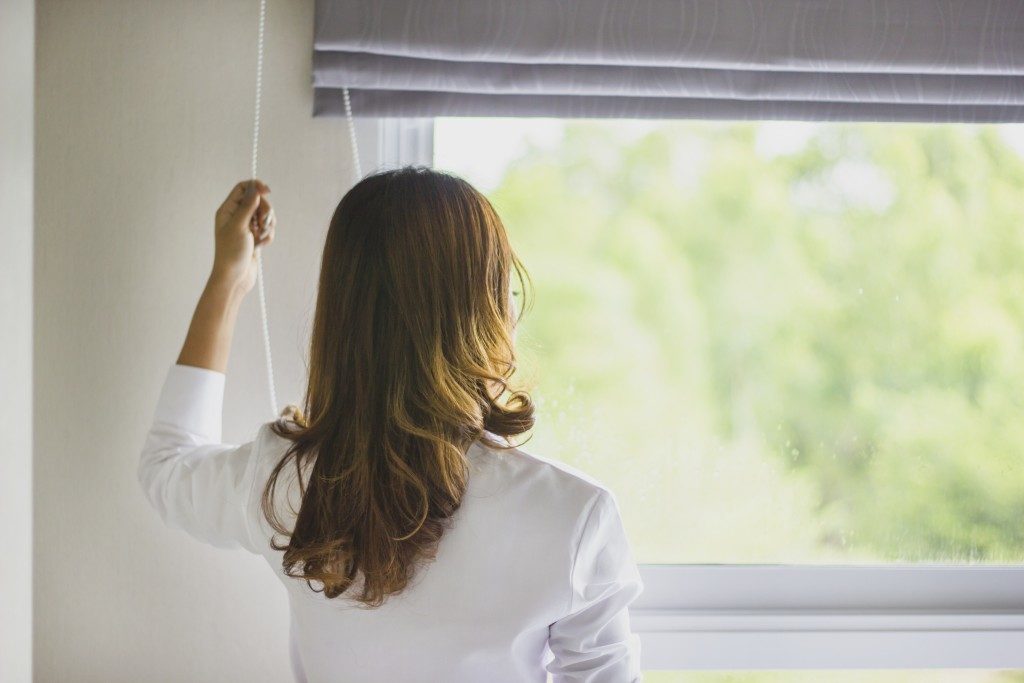 woman opening blinds of her window