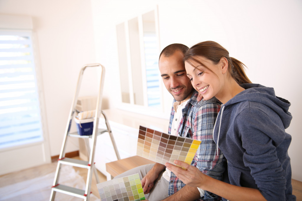 Young couple choosing the color for the walls of their home.
