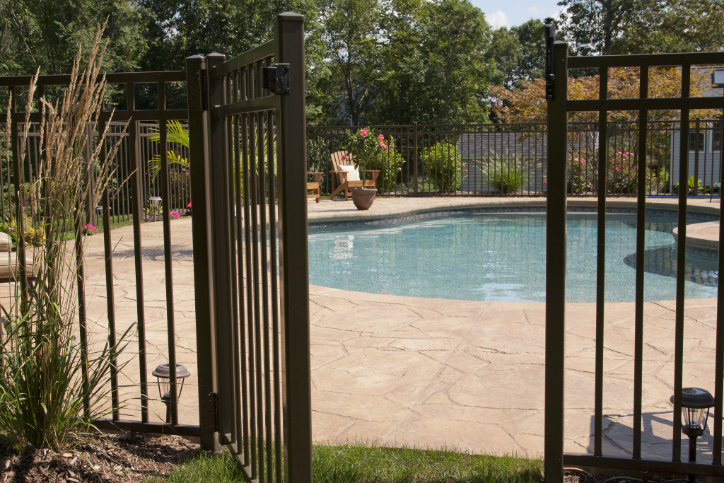 A backyard pool with a black gated fence