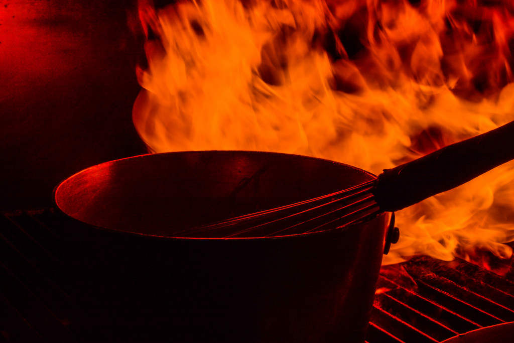 A saucepan on top of a grill on fire