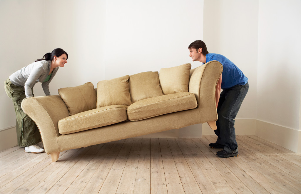 A couple moving their living room couch into an empty room
