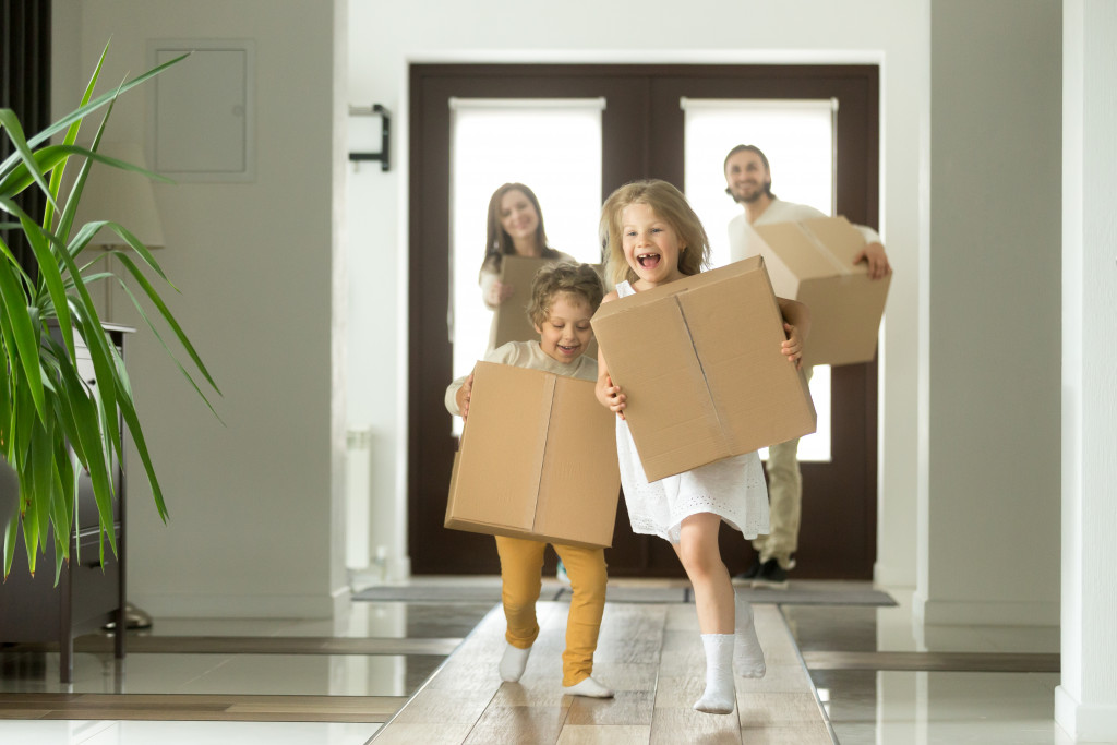 A happy family carrying moving boxes inside their new home