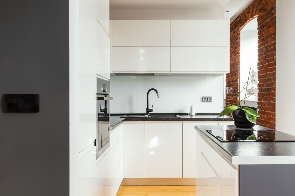 Small kitchen in white and grey colors and brick wall