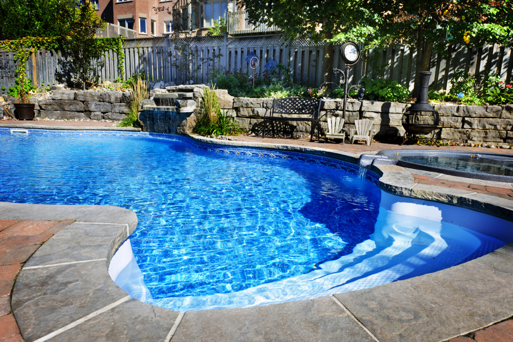 Curved swimming pool at home with landscaping along its side.