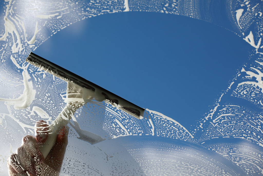 A person using a squeegee to clean a soapy window