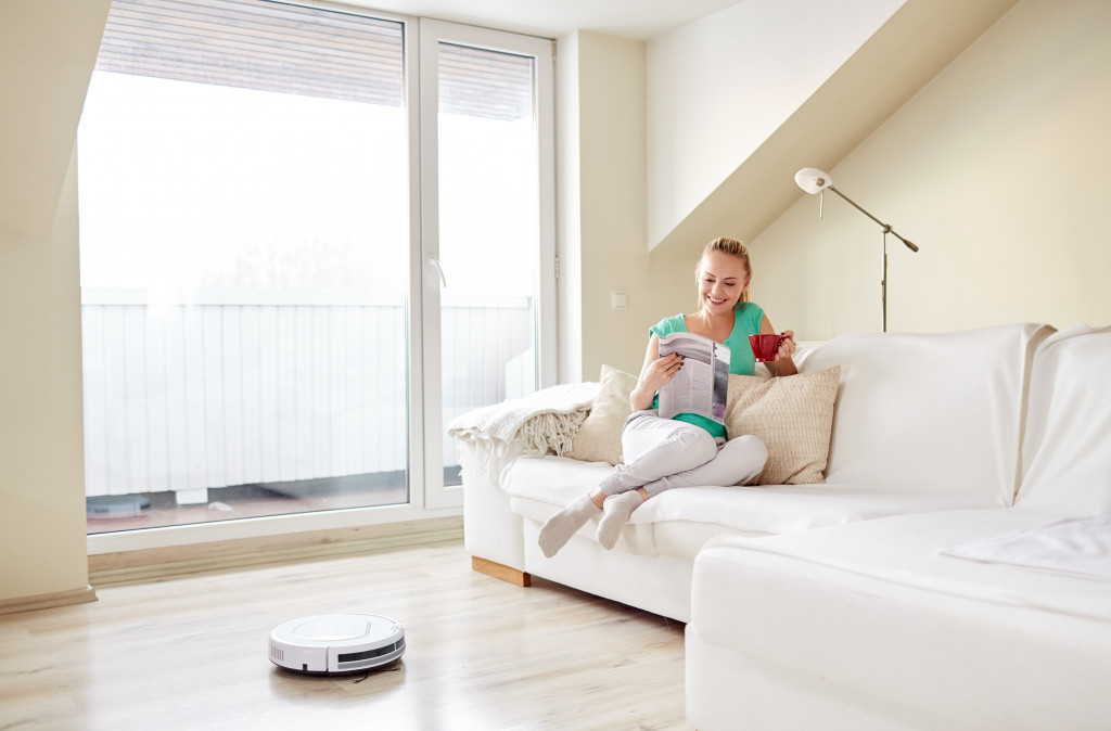 a woman sitting at the sofa with robot vacuum cleaner