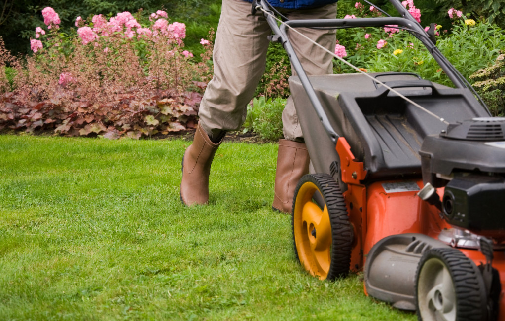 Professional gardener mowing the lawn of a house.
