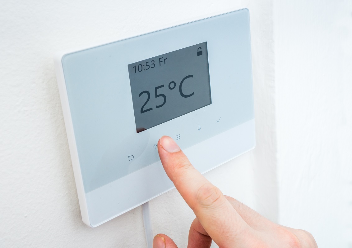 A finger touching a digital thermostat