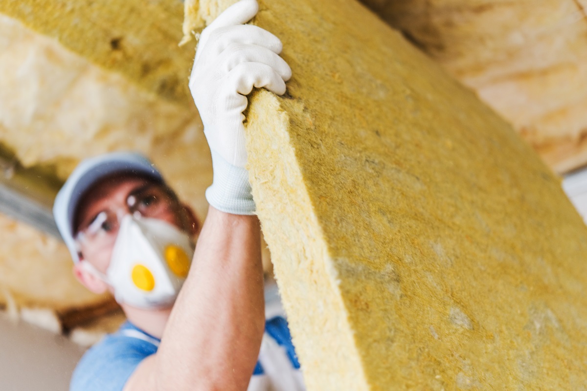 A worker carrying a slab of insulation